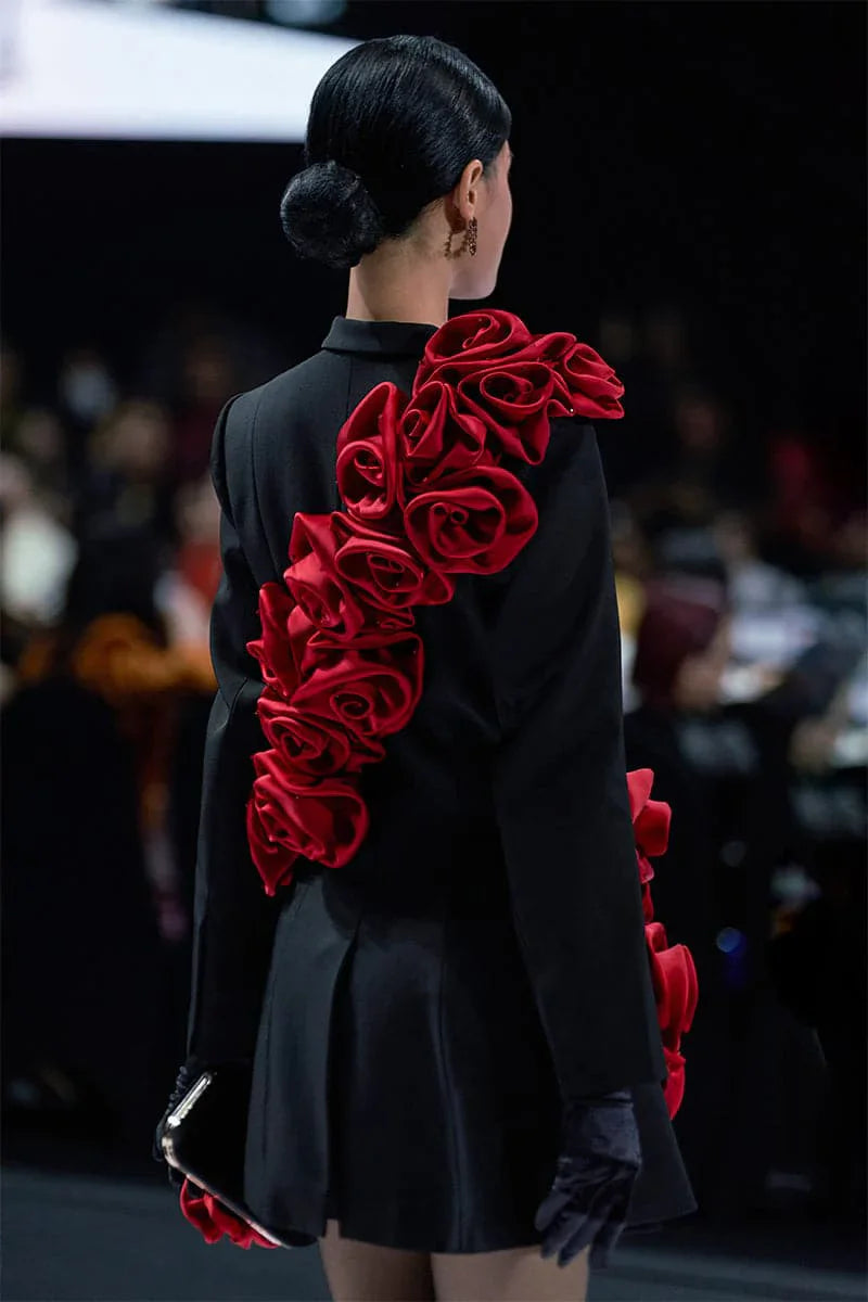 Back view of womens blazer dress showing red handmade flower embellishments on runway